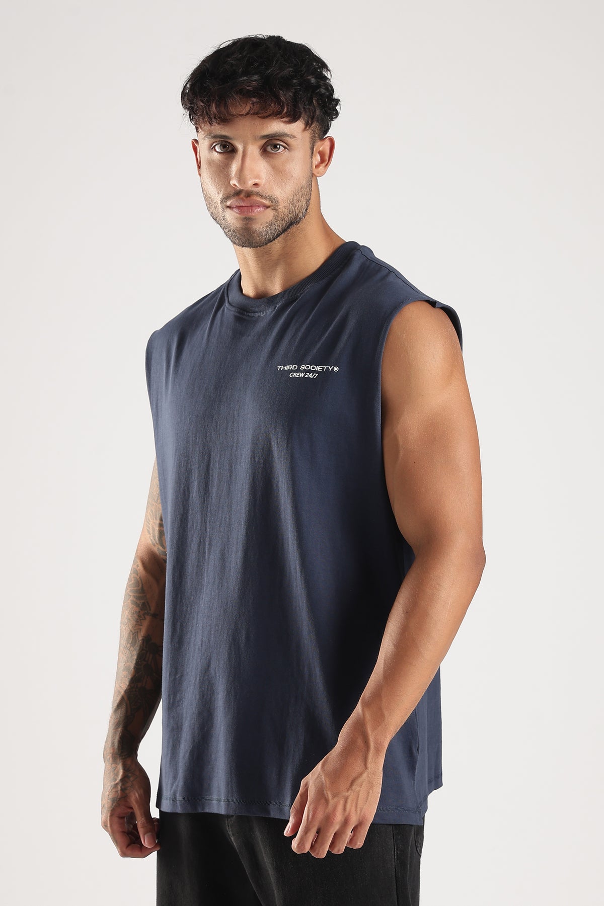 Close front view of a model wearing the Blue oversized tank top with Third Society Crew 24/7 branding