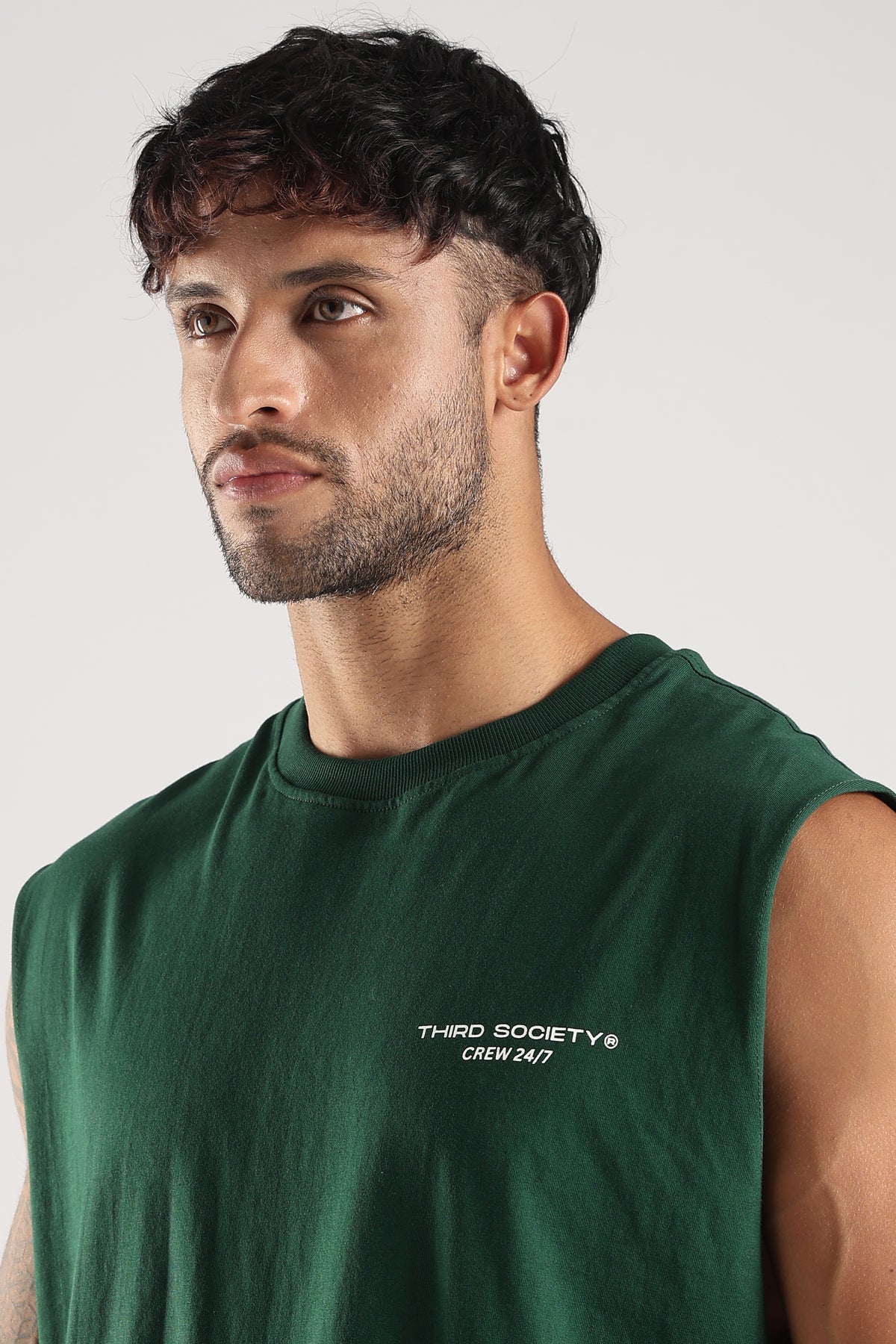 Close front view of a model wearing the Green oversized tank top with Third Society Crew 24/7 branding