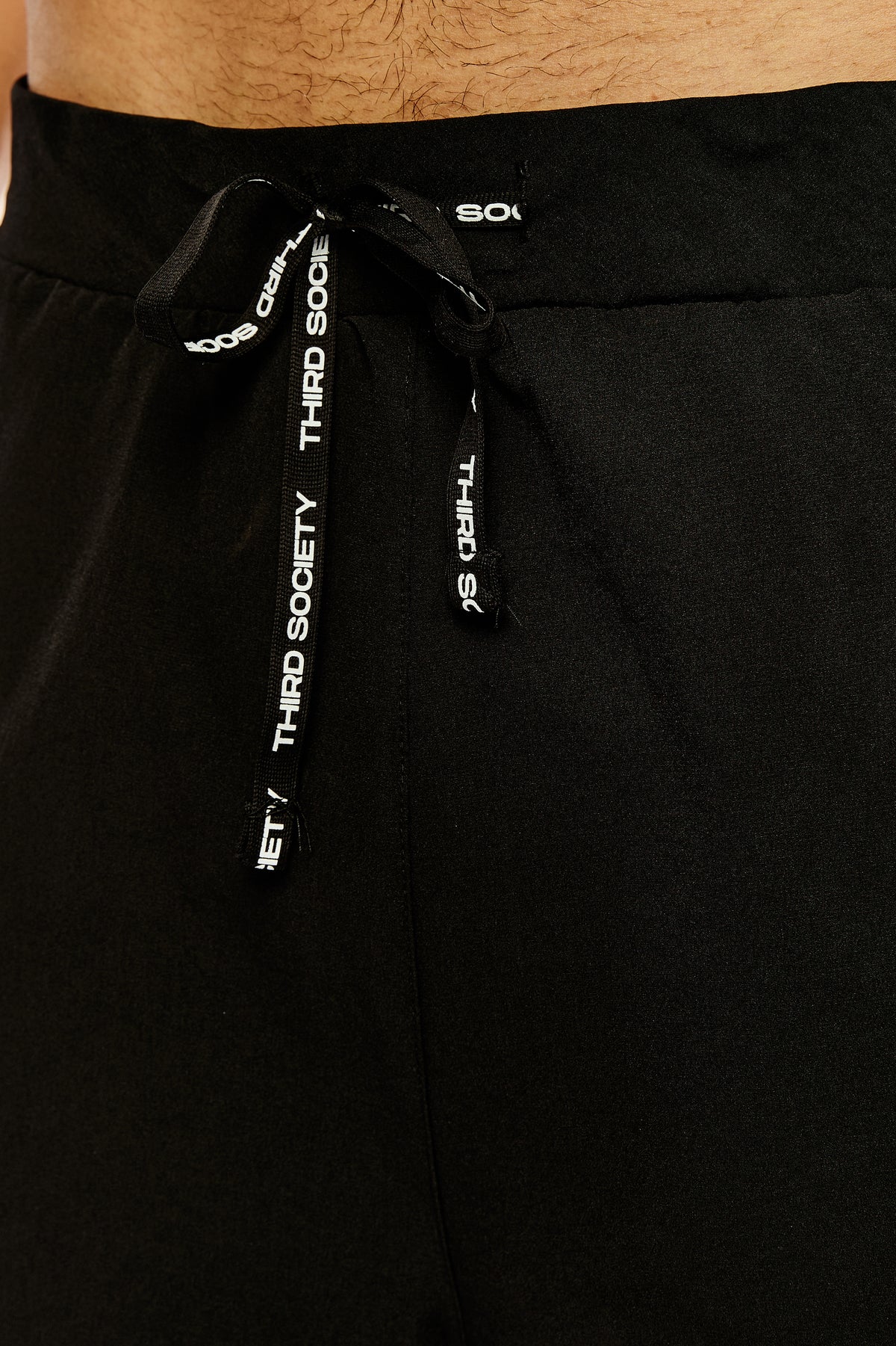 Close-up of the branded drawstring and waistband on black hybrid liner shorts