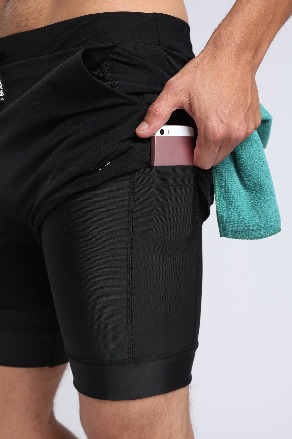 Close-up showing the side pocket of black hybrid liner shorts holding a phone