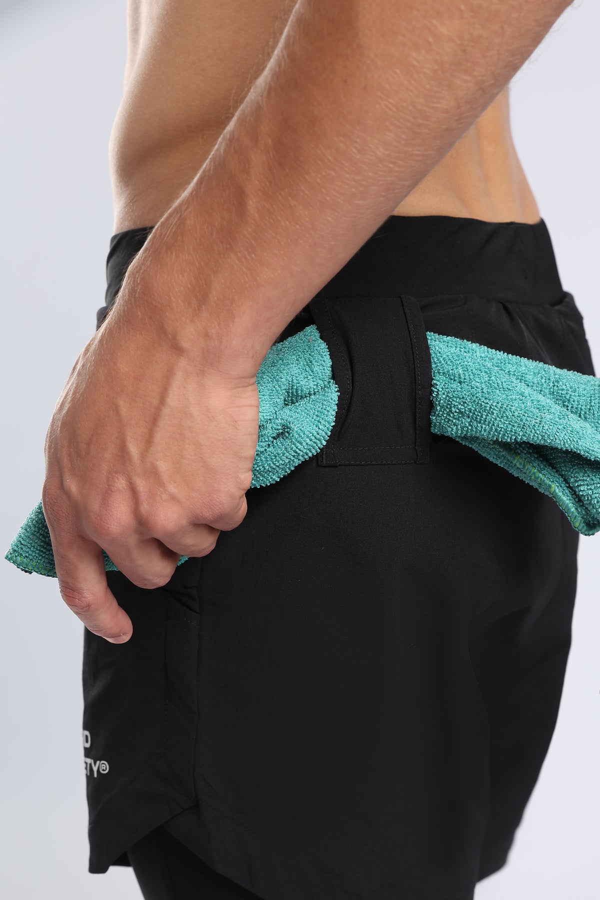 Close-up showing a towel secured through the rear loop of black hybrid liner shorts