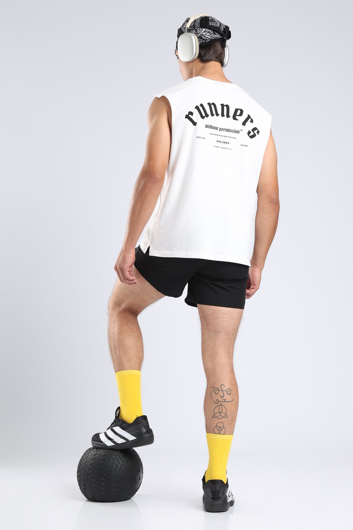 Model wearing the white tank with headphones, showing the runner-inspired back print
