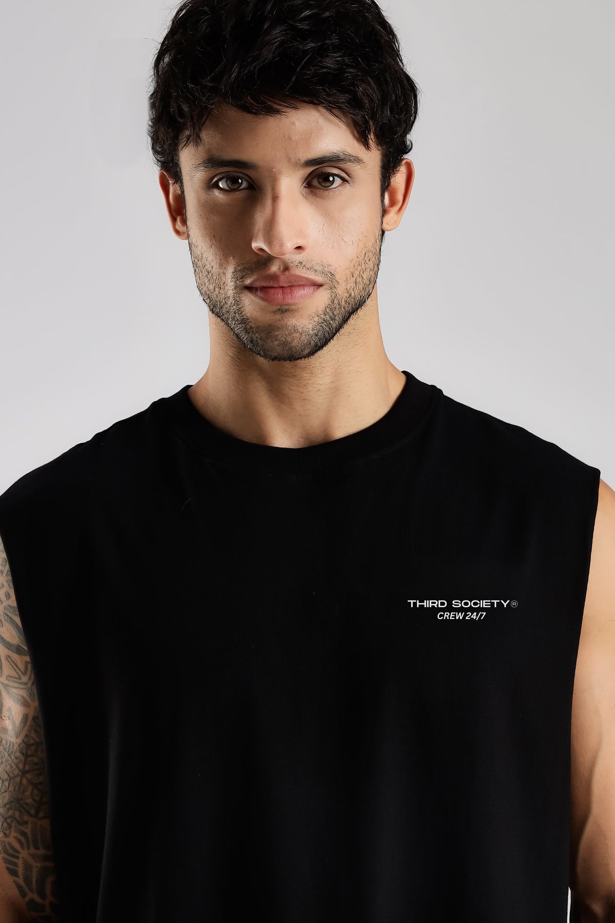 Close-up of the black Third Society tank top showing the Crew 24/7 chest branding