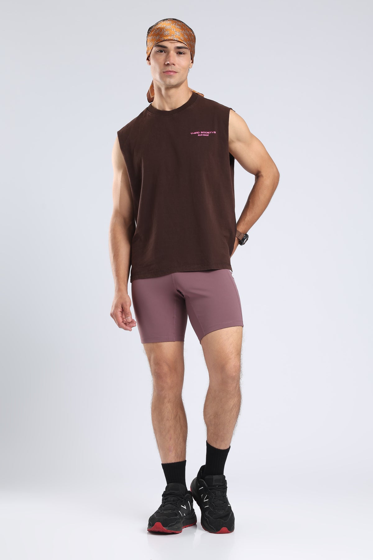 Model wearing the Burnt Umber Wash tank with mauve running shorts and a patterned bandana