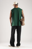 Back view of a model wearing the Forest Green oversized tank top with black trousers