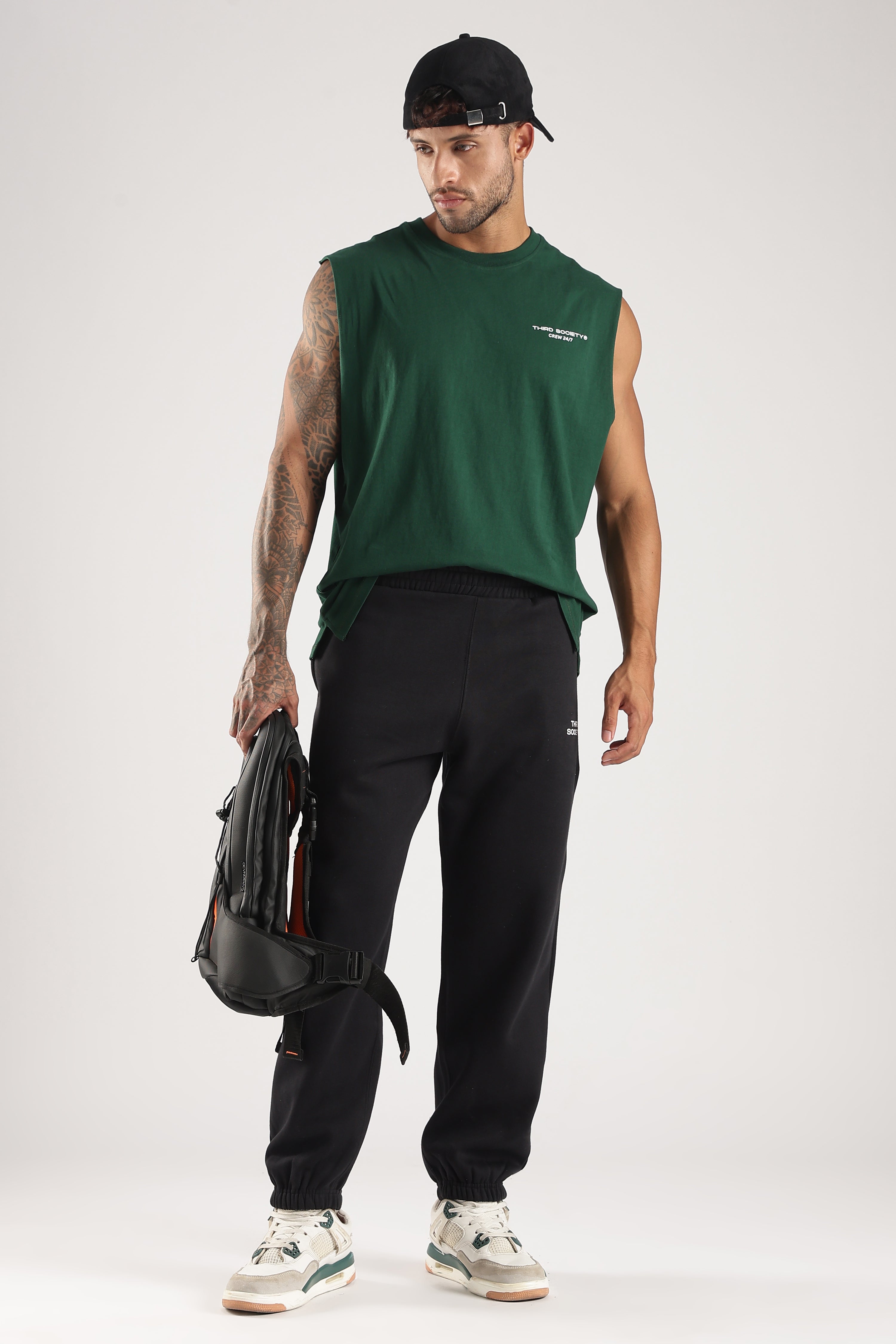 Model wearing the Forest Green Third Society tank top with black joggers and a backpack