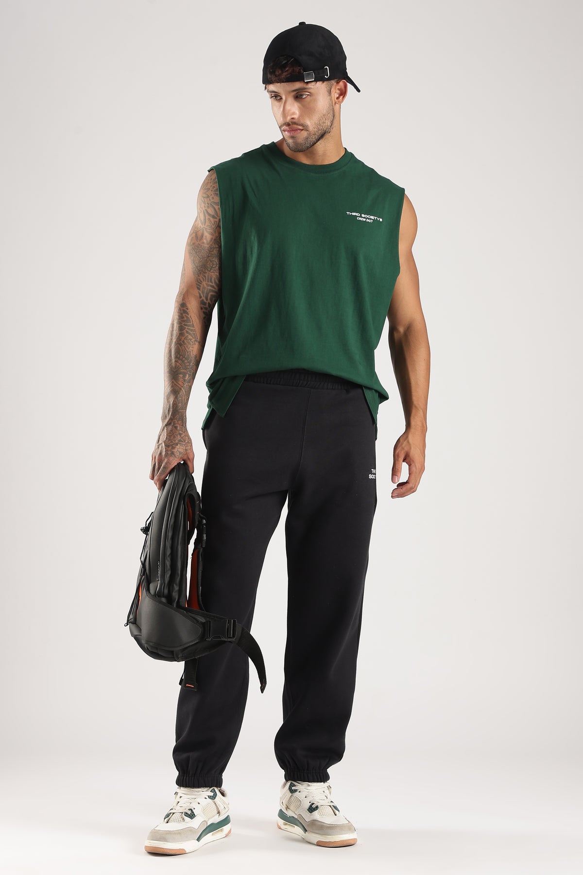 Model wearing the Forest Green Third Society tank top with black joggers and a backpack