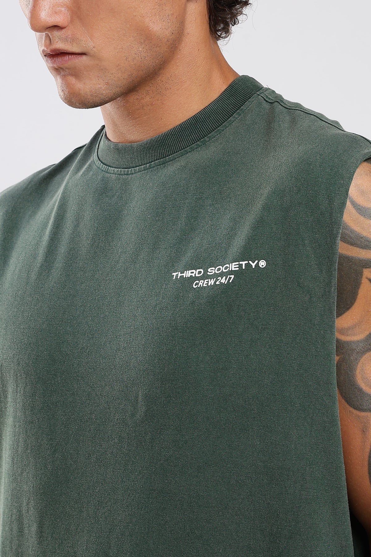 Close-up of Forest Moss tank top showing the Third Society chest logo and ribbed neckline