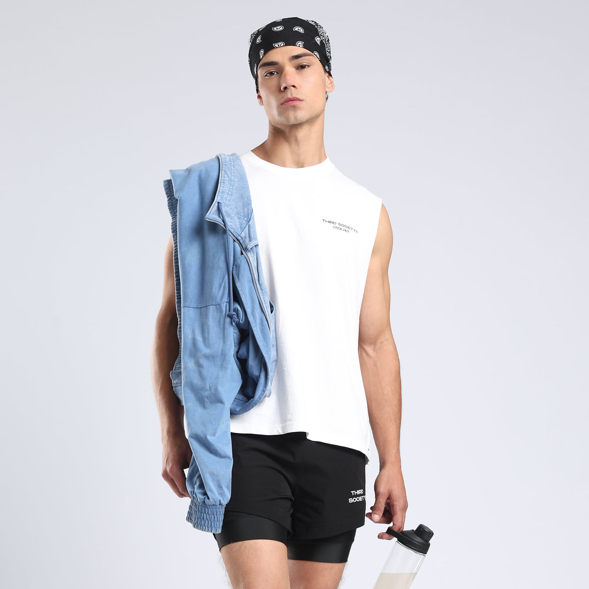 Model wearing the White Hybrid Athletes tank with a blue jacket and black shorts