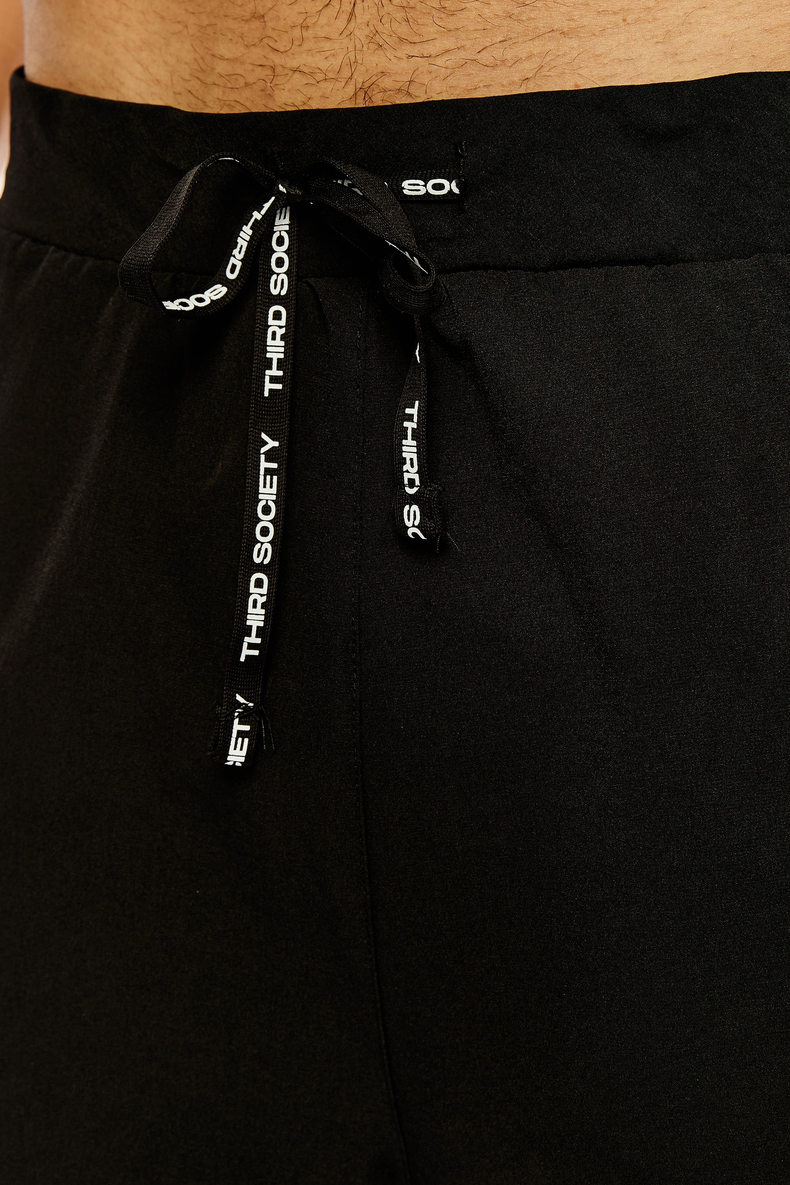 Close-up of the branded drawstring and waistband on black hybrid liner shorts
