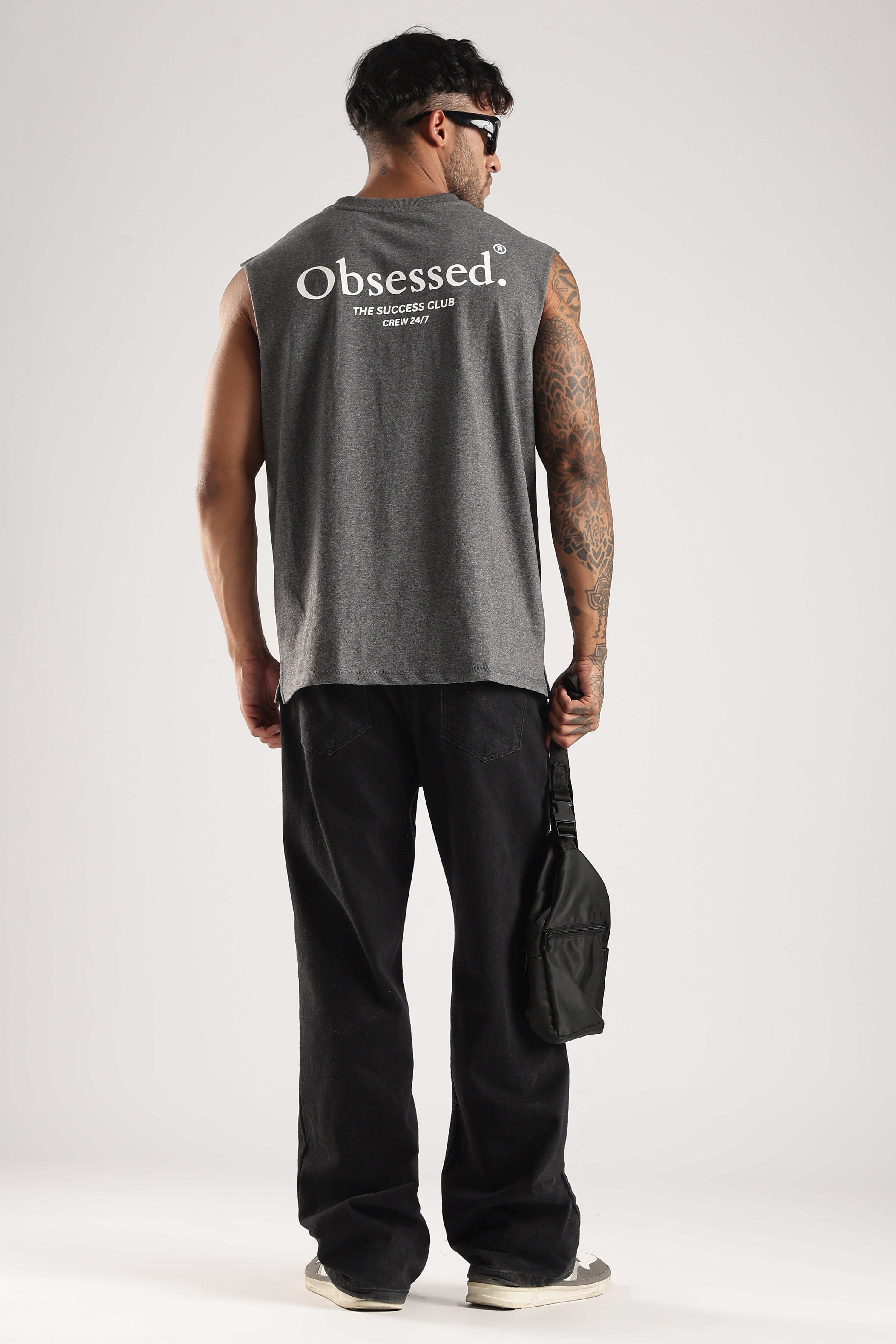 Model wearing the Grey Marl Obsessed Tank from the back with the Success Club graphic and crossbody bag