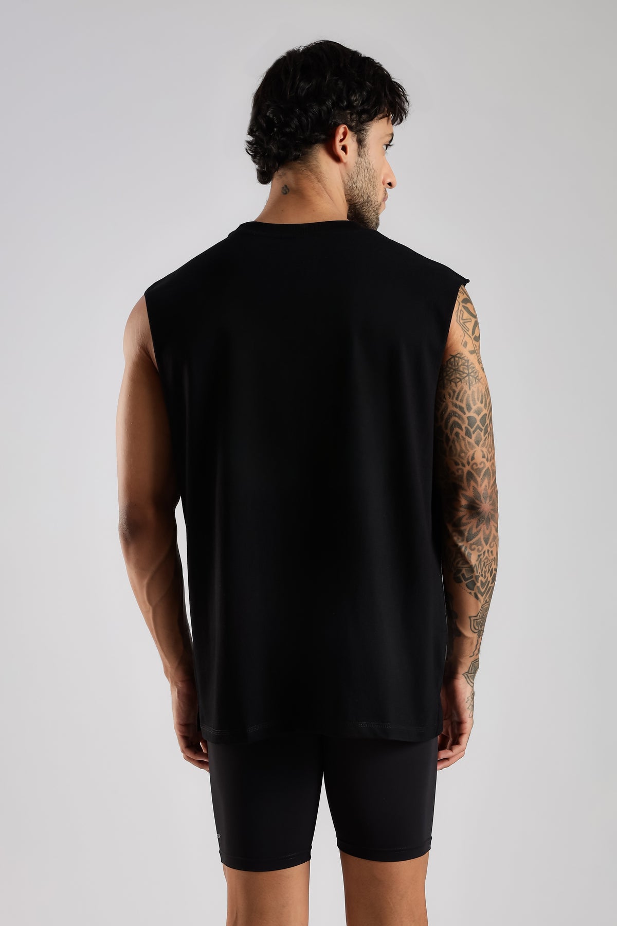 Back view of the model wearing the black Third Society oversized tank top