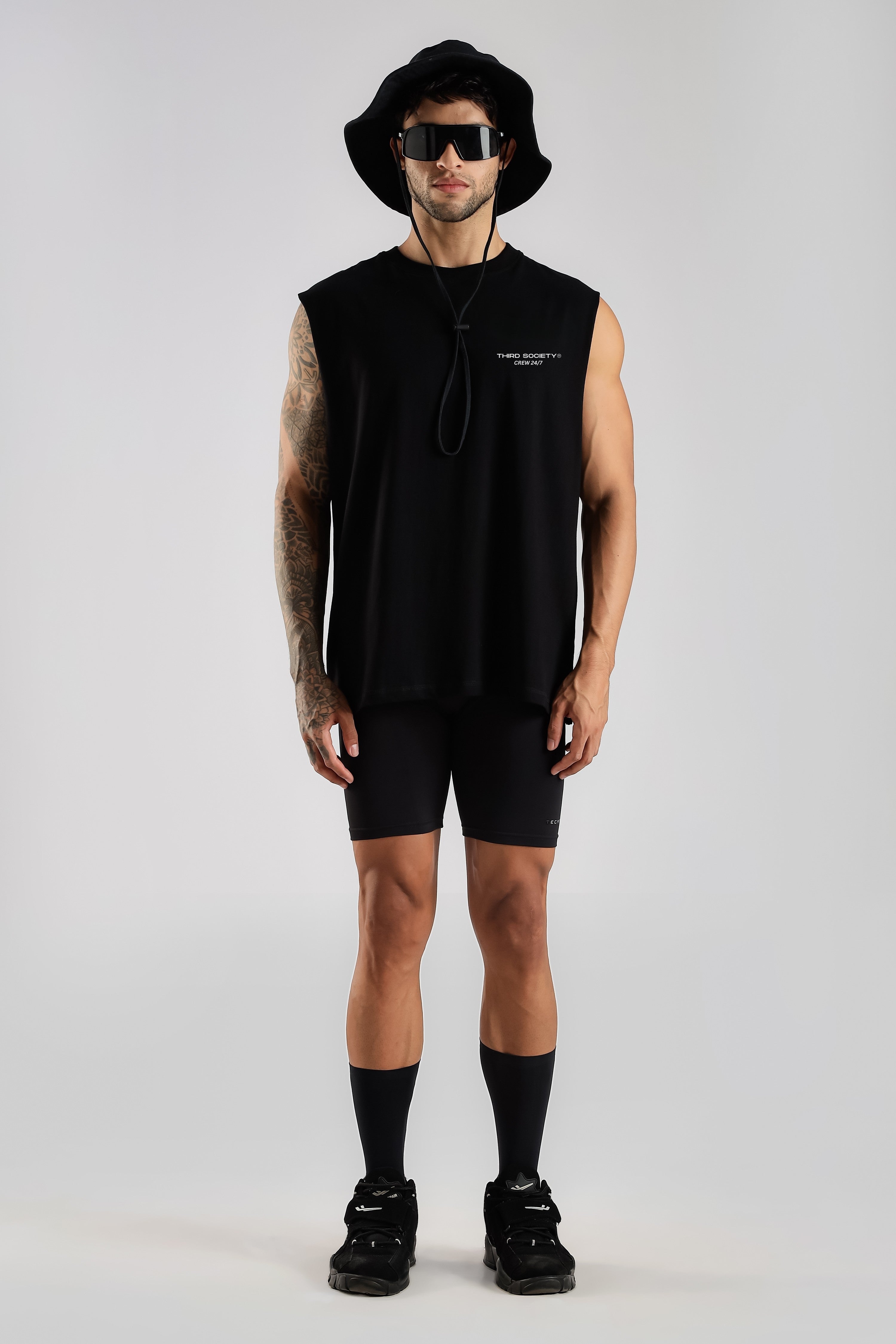 Model wearing the black Third Society tank top with a bucket hat and sunglasses
