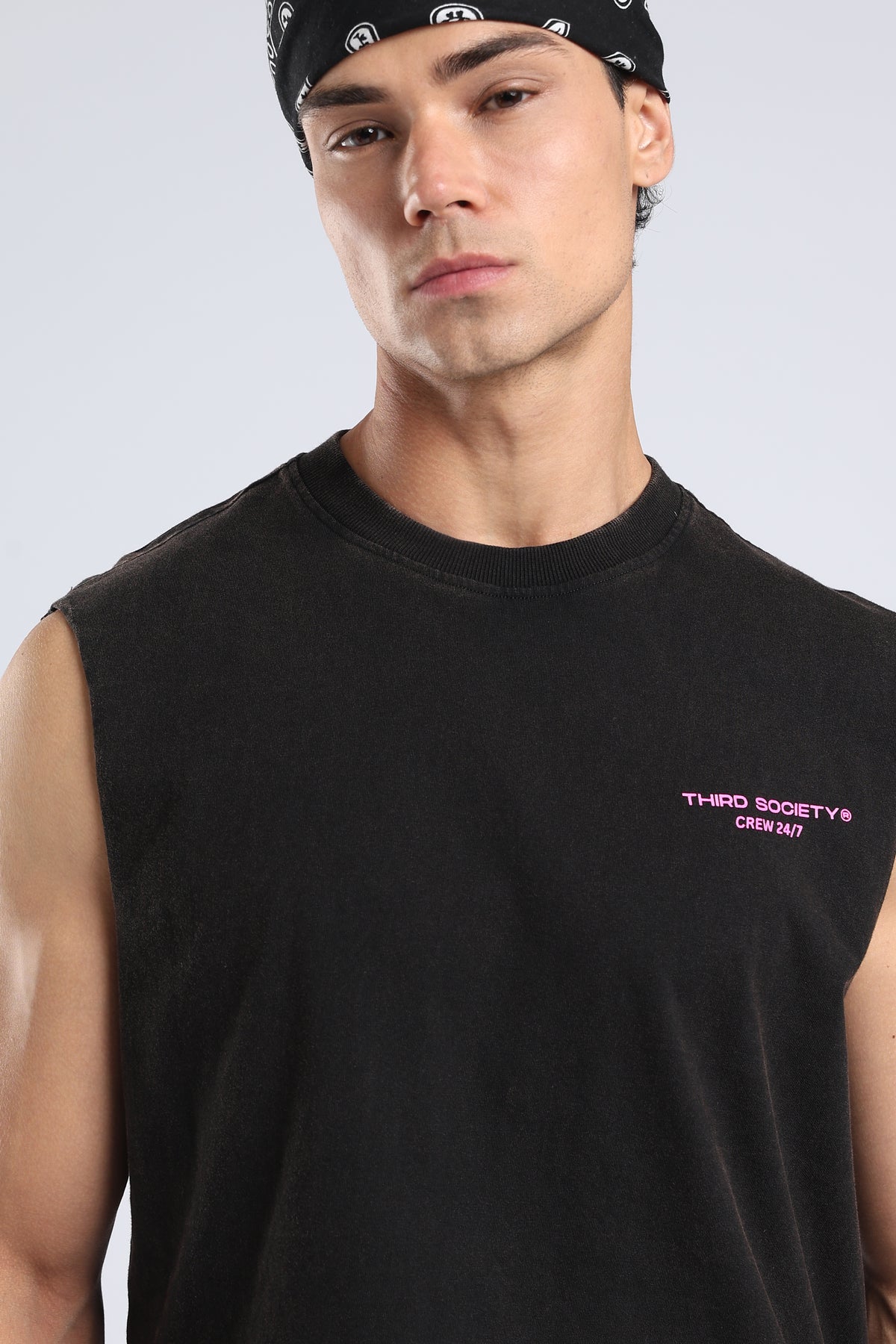 Close-up of the pink Third Society Crew 24/7 chest logo on the Carbon Wash tank
