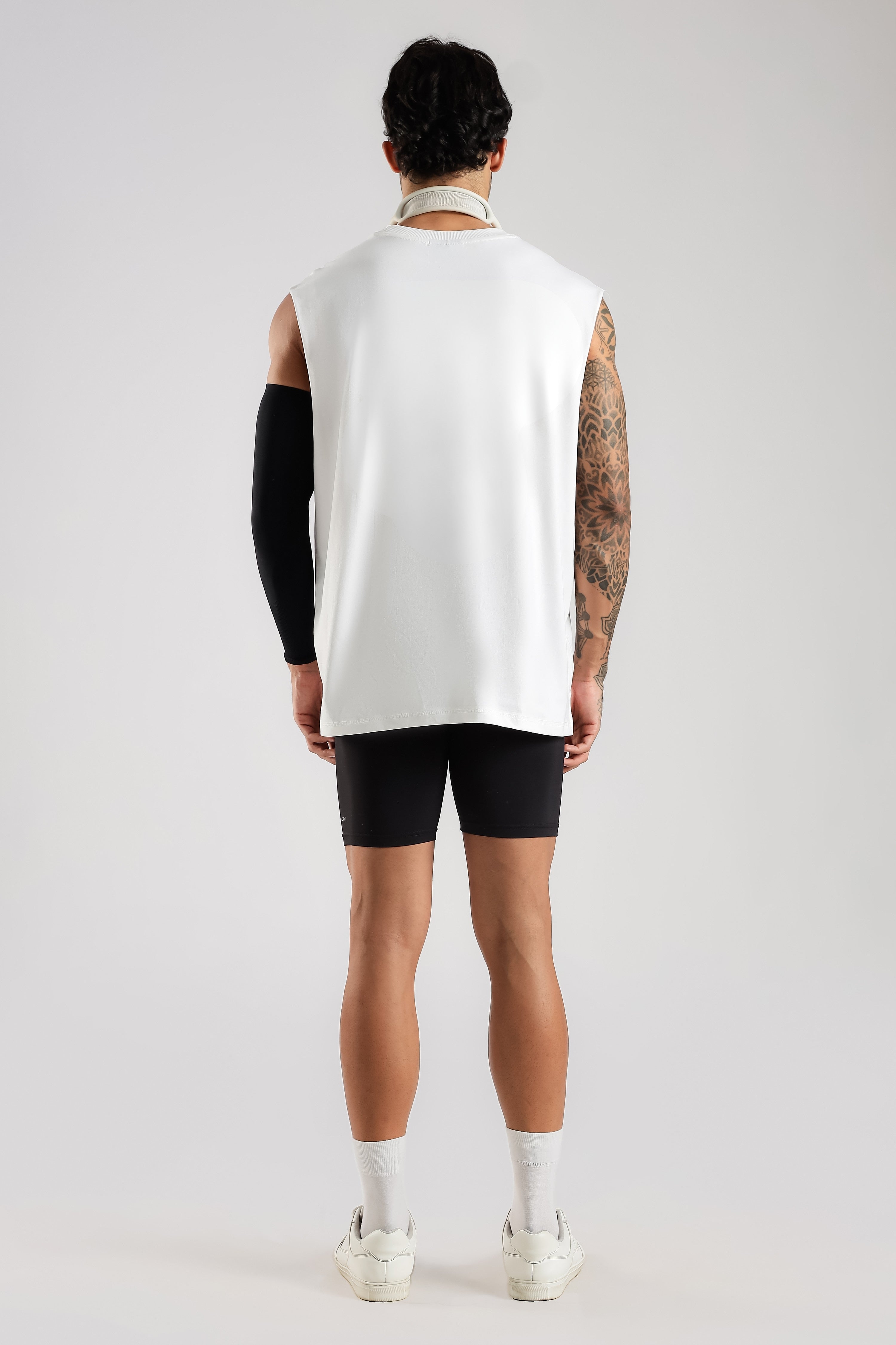 Back view of the model wearing the White Third Society oversized tank with black shorts