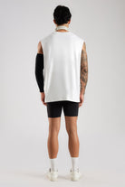 Back view of the model wearing the White Third Society oversized tank with black shorts