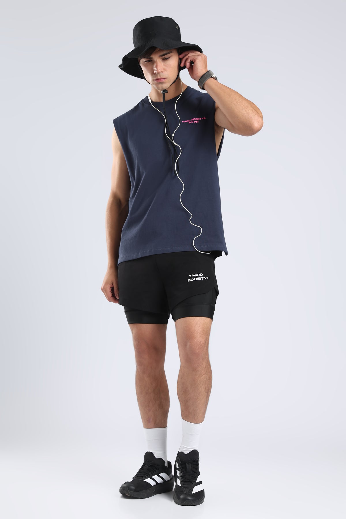 Front view of the Iron Blue tank styled with black shorts and a black bucket hat